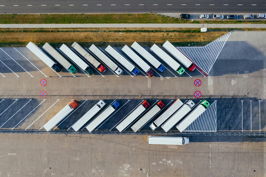 Vista aérea de camiones estacionados ordenadamente en un centro logístico, un ejemplo de la coordinación de transporte que ofrece Del Bravo Trade